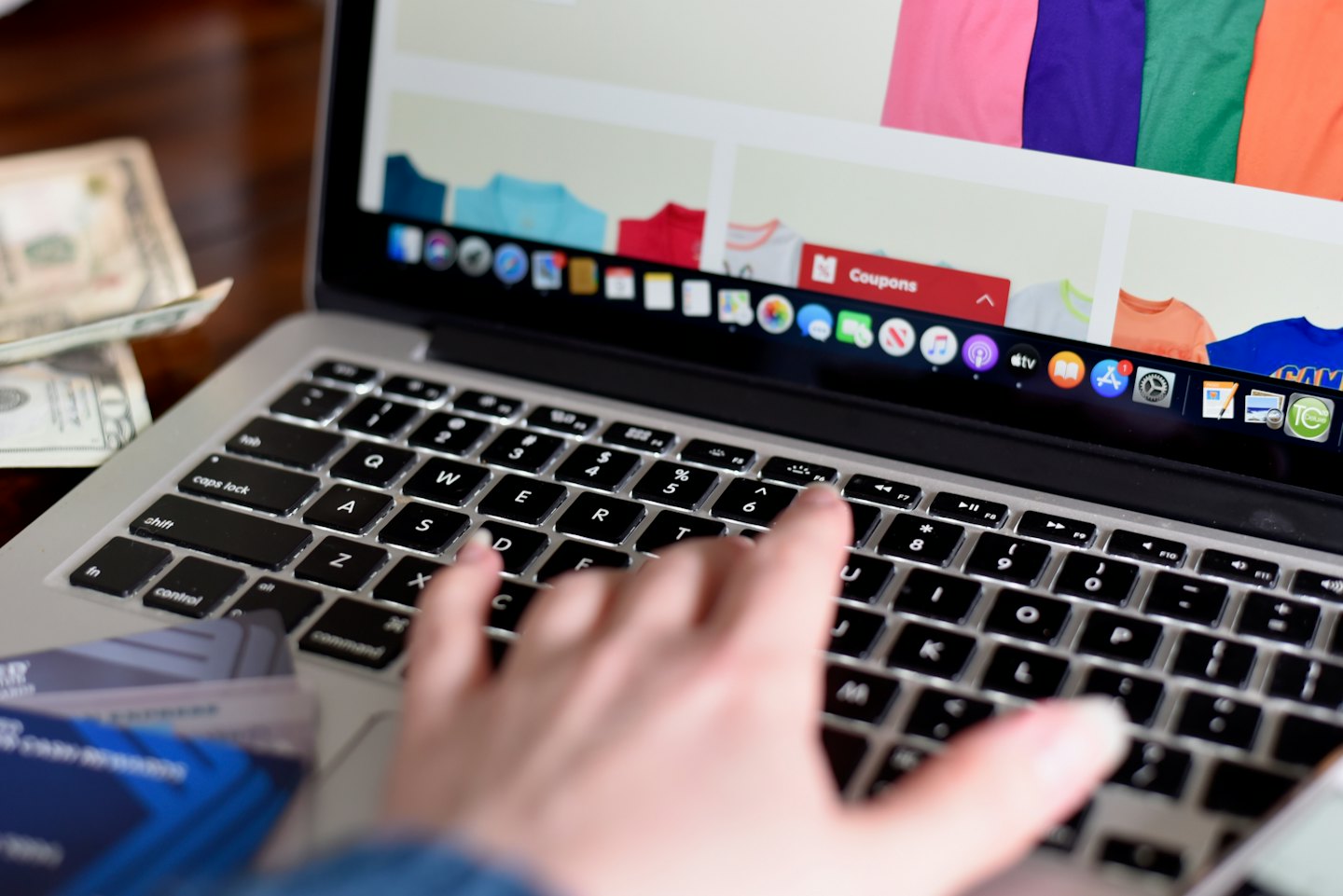 Home Hand typing on a silver laptop keyboard during online shopping.