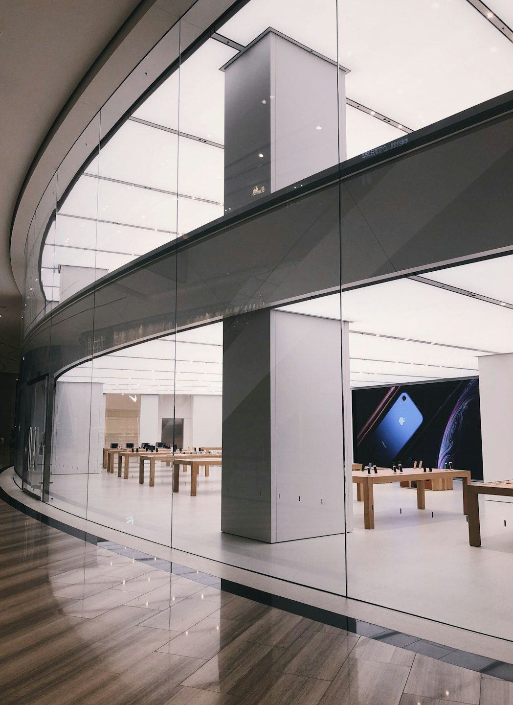 Electronic devices displayed on wooden tables inside a modern store.