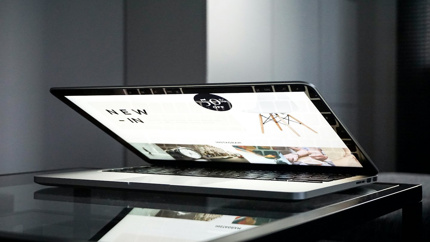 Home Laptop screen showing e-commerce website on a reflective surface.