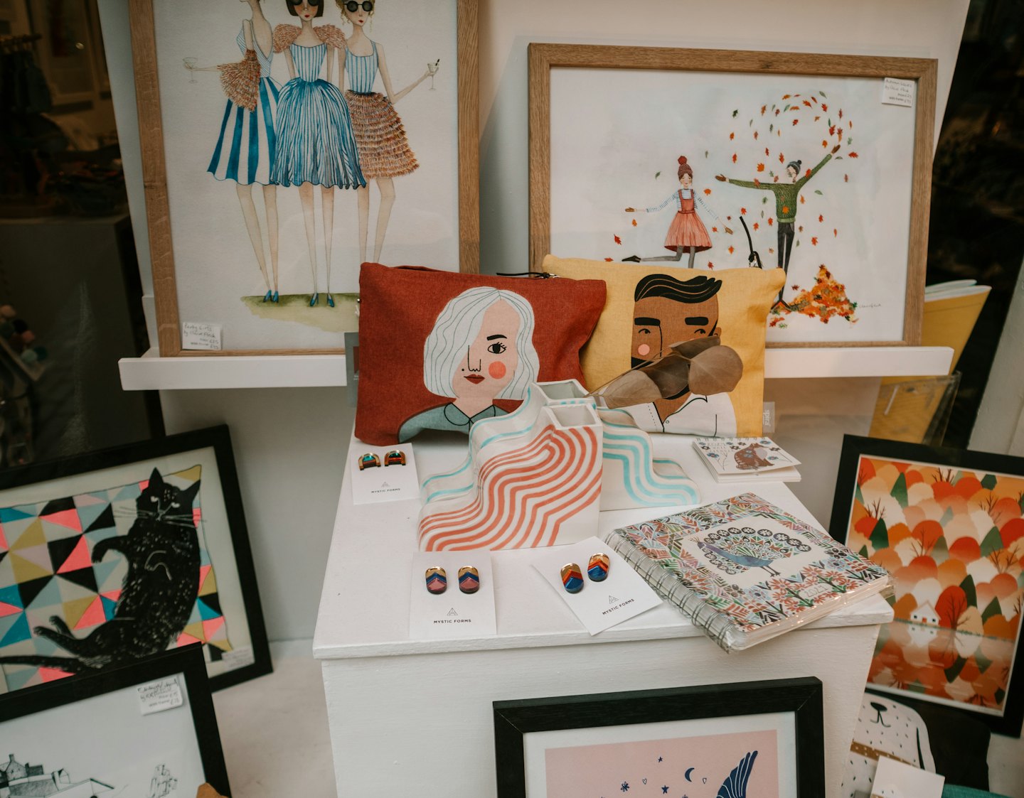 Specials Retail shelves displaying illustrated artwork, decorative cushions, and small earrings.