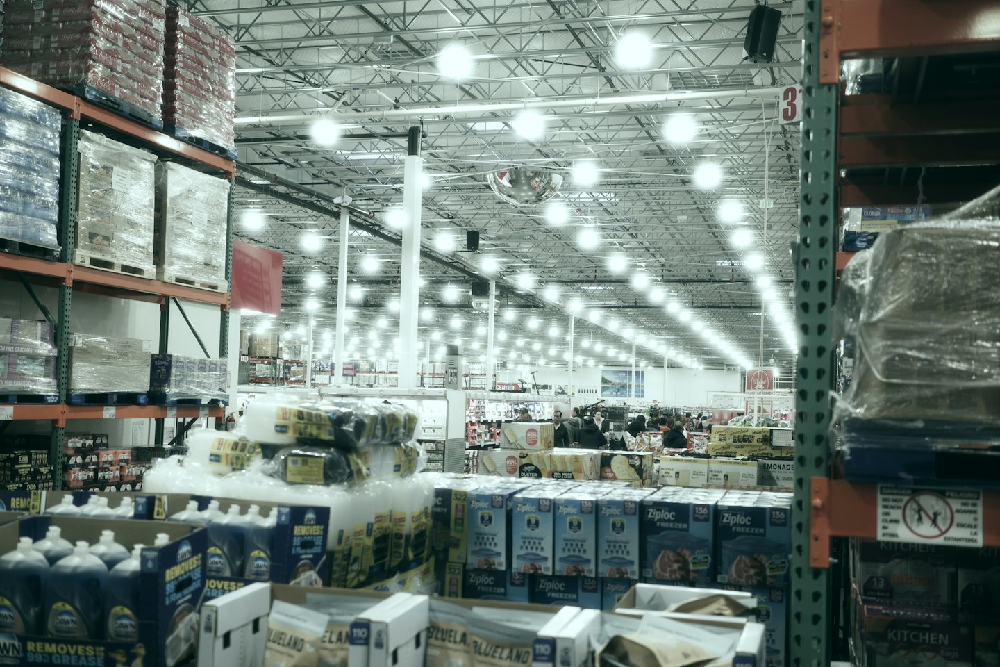Home Customers browsing in a brightly lit warehouse store with tall shelves.